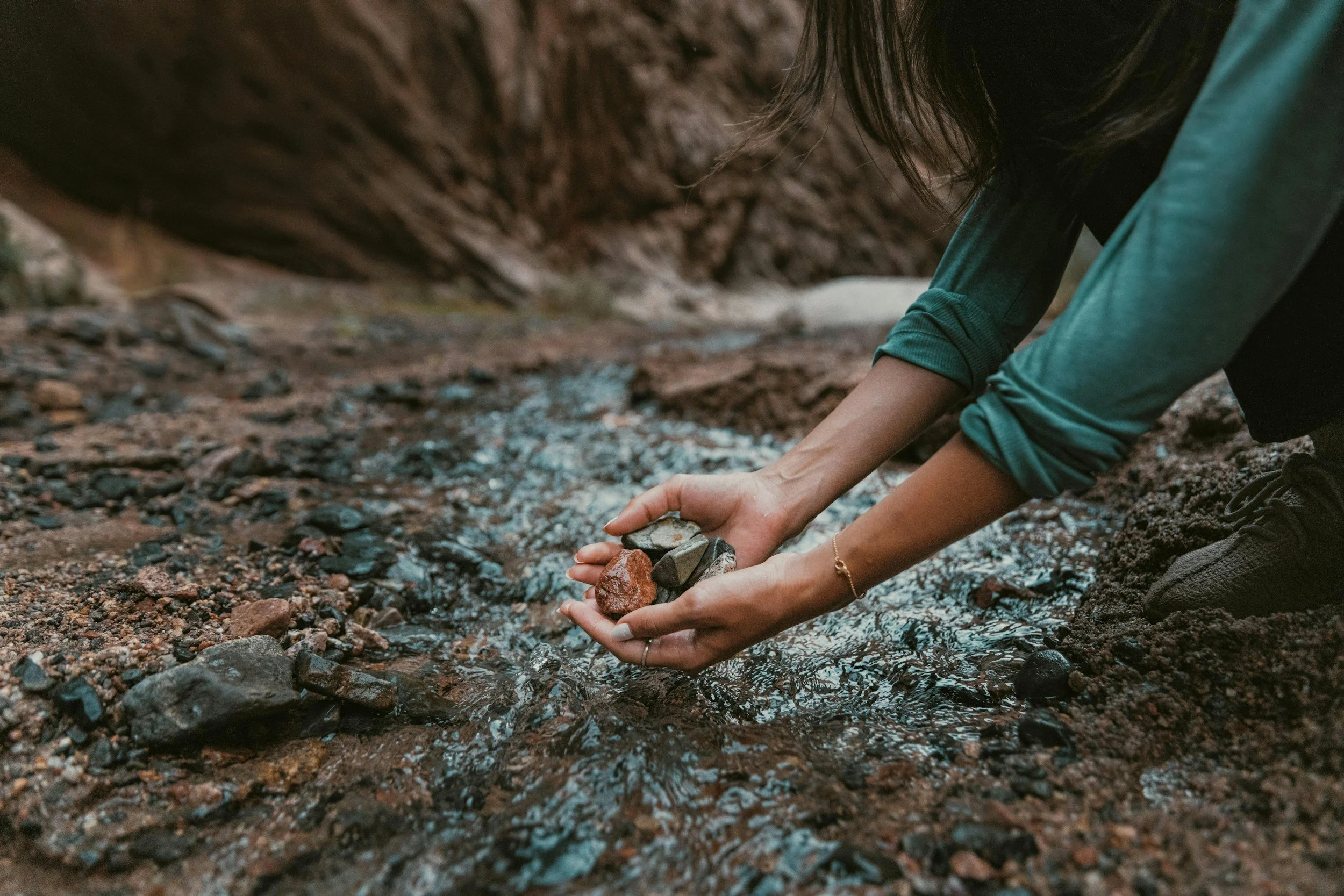 woman shifting rocks in her hands over a stream