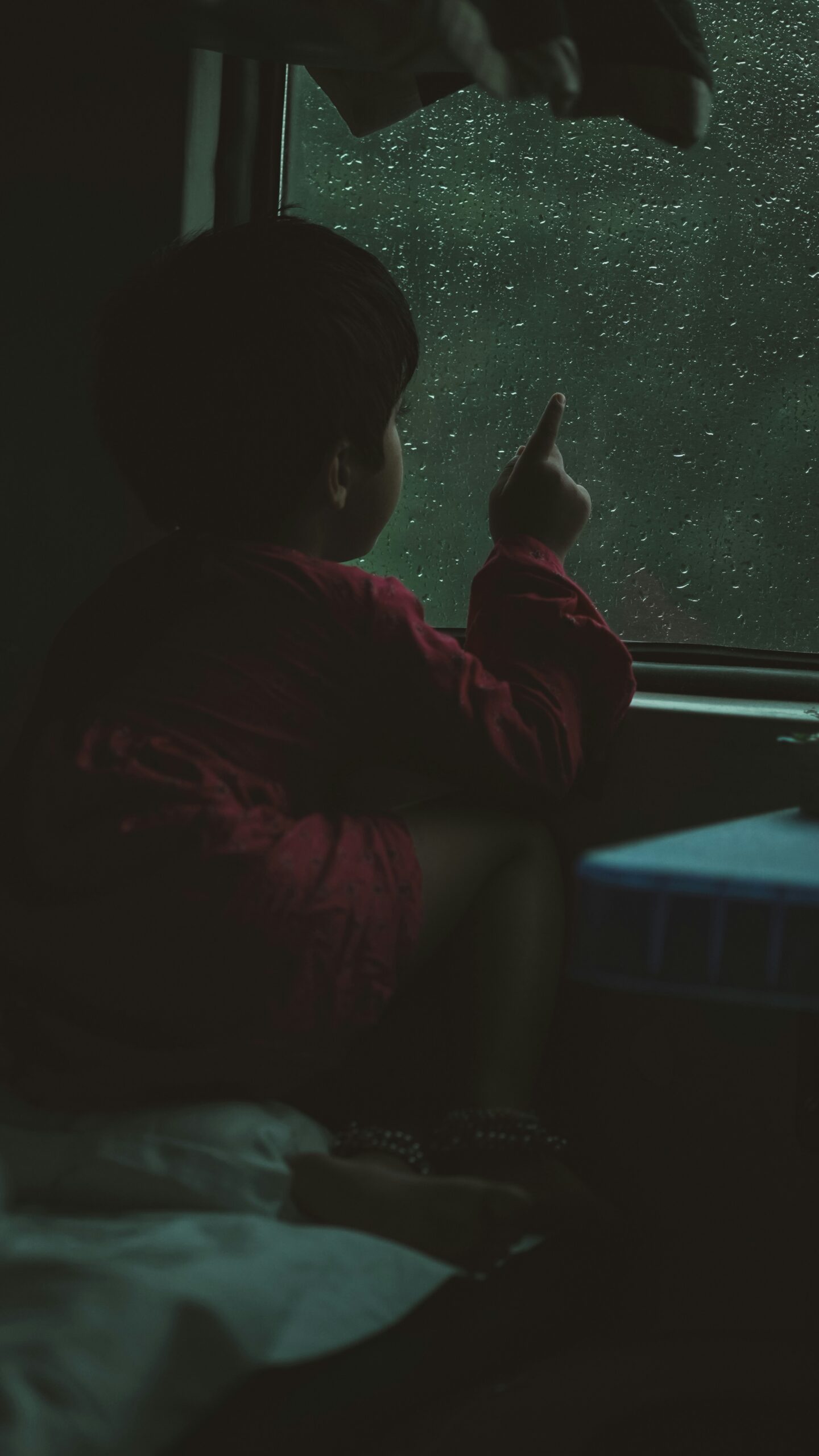 small child looking out a rainy window